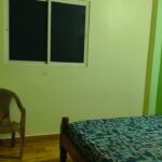 Bedroom showing wall-mounted air conditioner, wooden bed and window