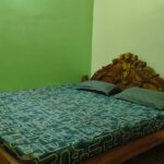 Guest bedroom with wooden bed and pillows, accommodation near Lighthouse in Puri